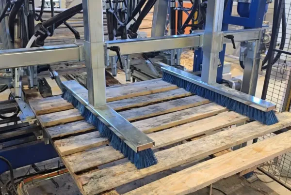 Das fertige Palettendeck fährt unter den Bürsten der IMH Machinery Deckmaschine hervor