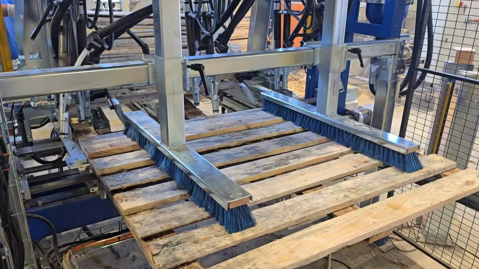 Das fertige Palettendeck fährt unter den Bürsten der IMH Machinery Deckmaschine hervor